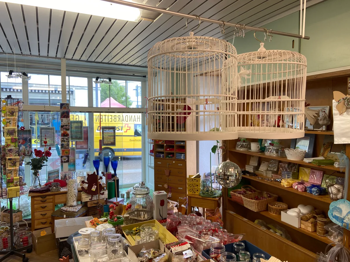 Viele Einwohnerinnen aus der Gemeinde Wald sind gar nicht glücklich darüber, dass der Laden bald nicht mehr geöffnet ist. Ein Ladengeschäft. An der Decke hängen Vogelhäuser.